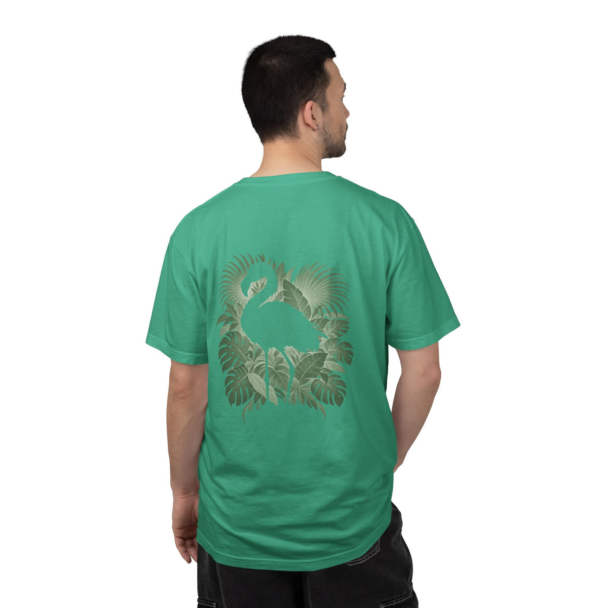 Model wearing the Island Green Hidden Flamingo T-shirt, showing a flamingo silhouette framed by tropical leaves on the back.