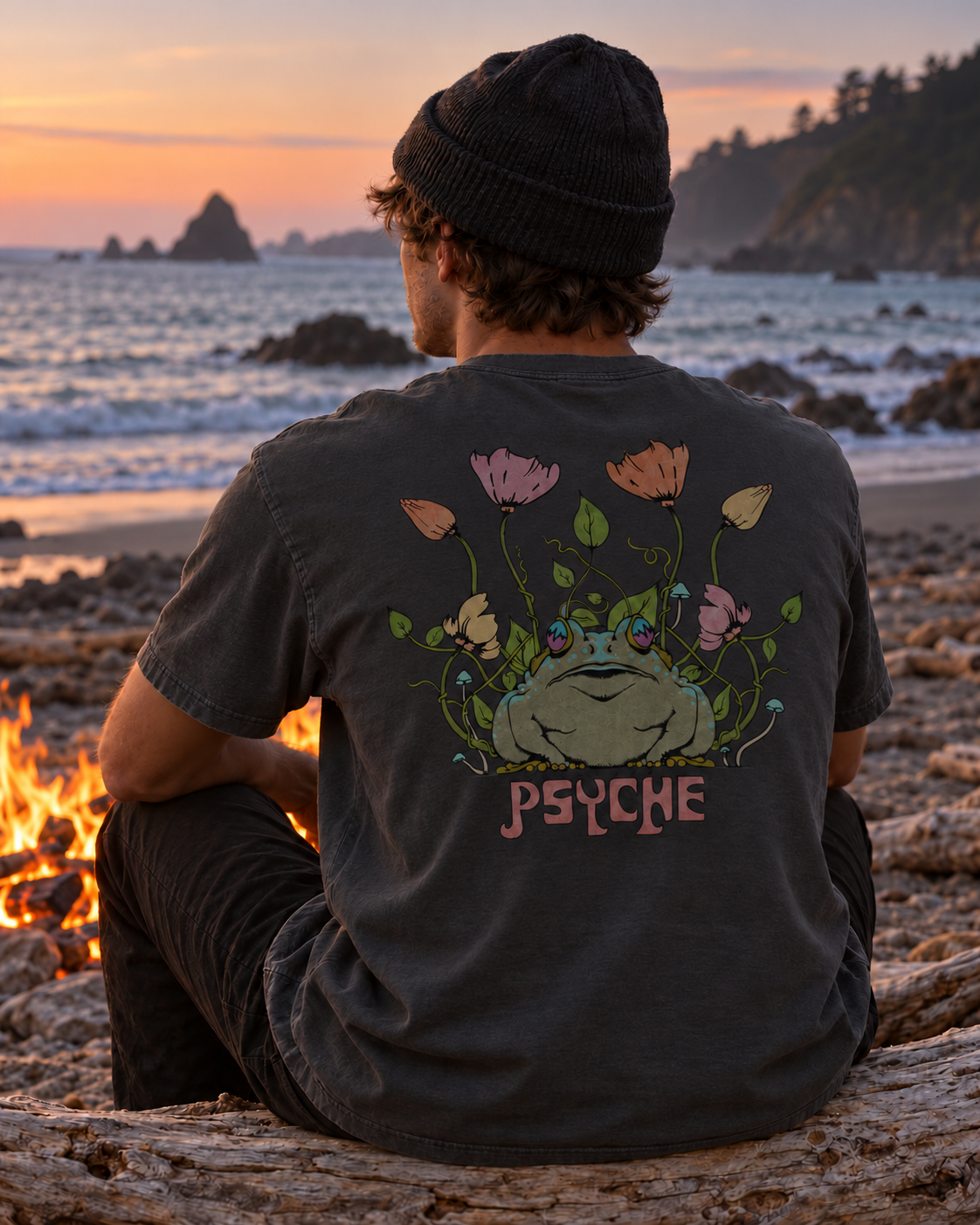 Man wearing the Pepper Psyche Toad t-shirt beside a beach campfire at sunset, showing the nature artwork on the back.